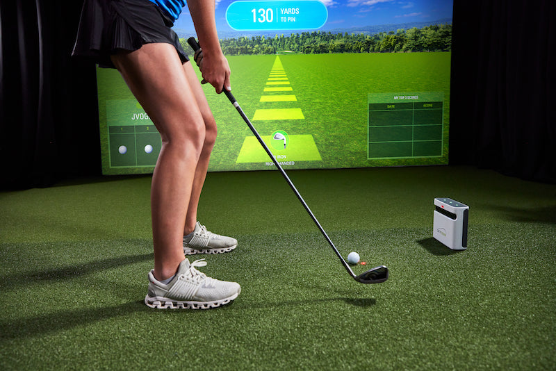 Woman hitting on a golf simulator powered by SkyTrak plus launch monitor