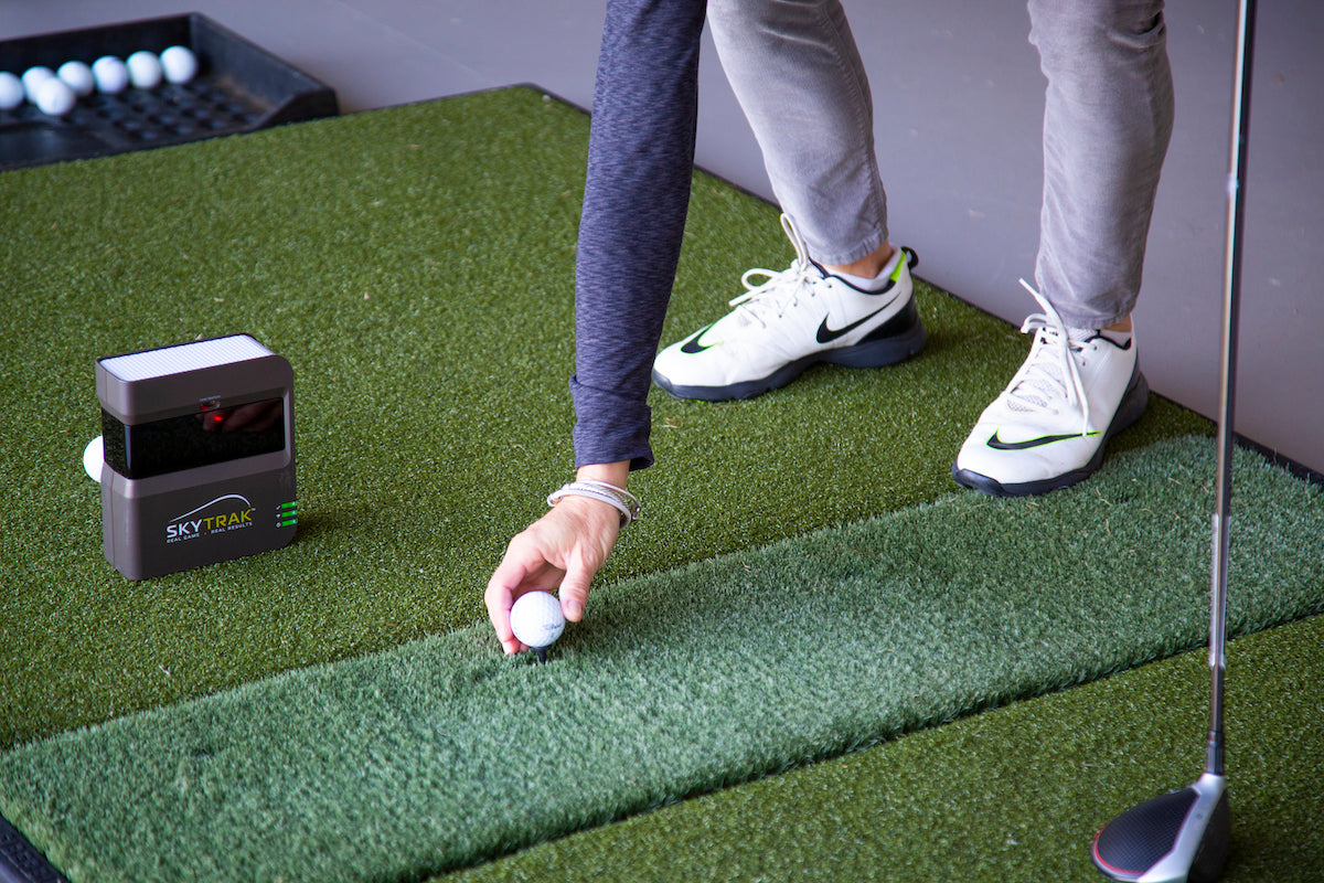 Woman teeing up a golfball to hit a shot on the SkyTrak launch monitor