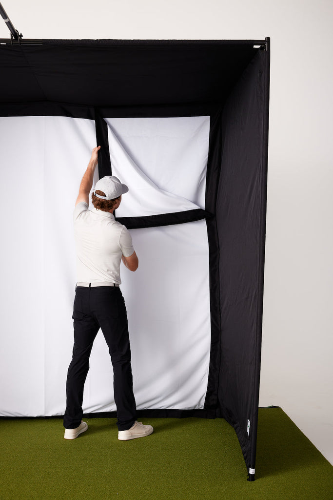 Man attaching impact screen to SkyTrak golf simulator studio enclosure